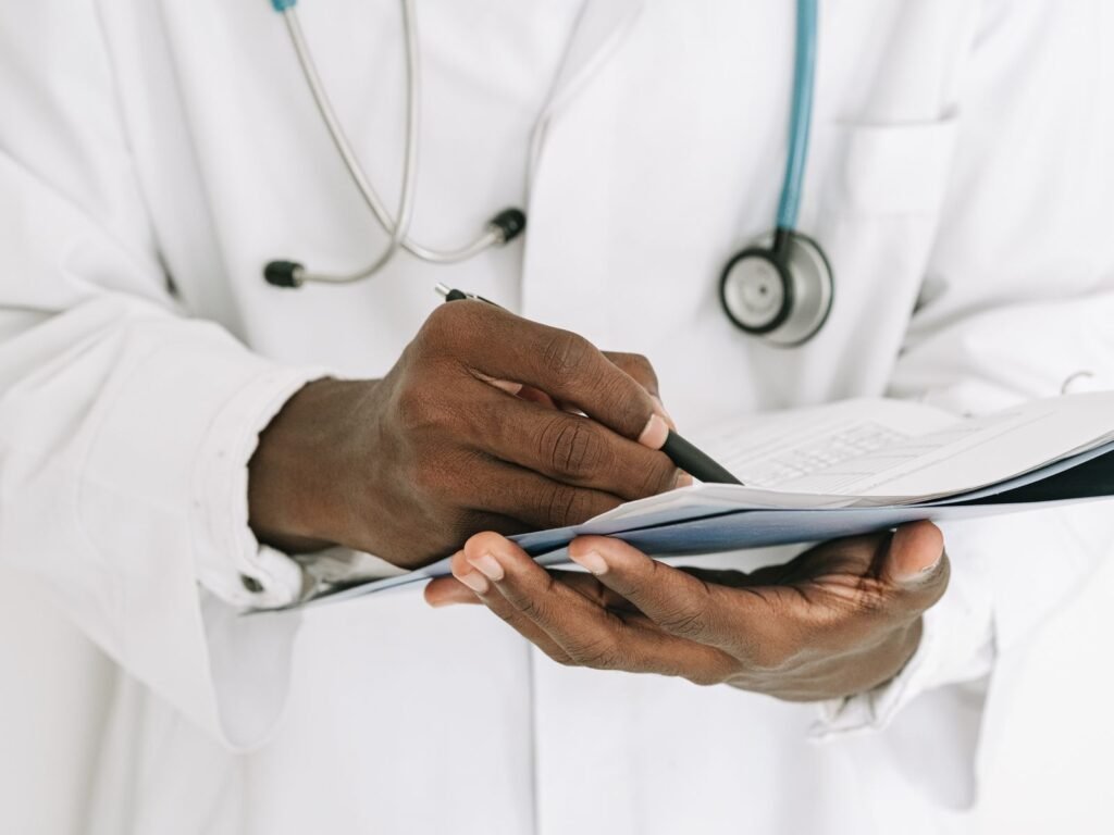 A physician writing notes on a clipboard in a medical office.